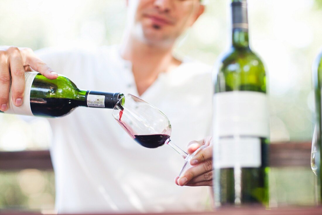 A man pouring a glass of red wine