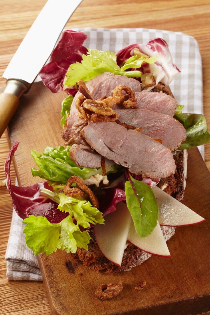 Country bread topped with roast wild boar, sliced apple and lettuce