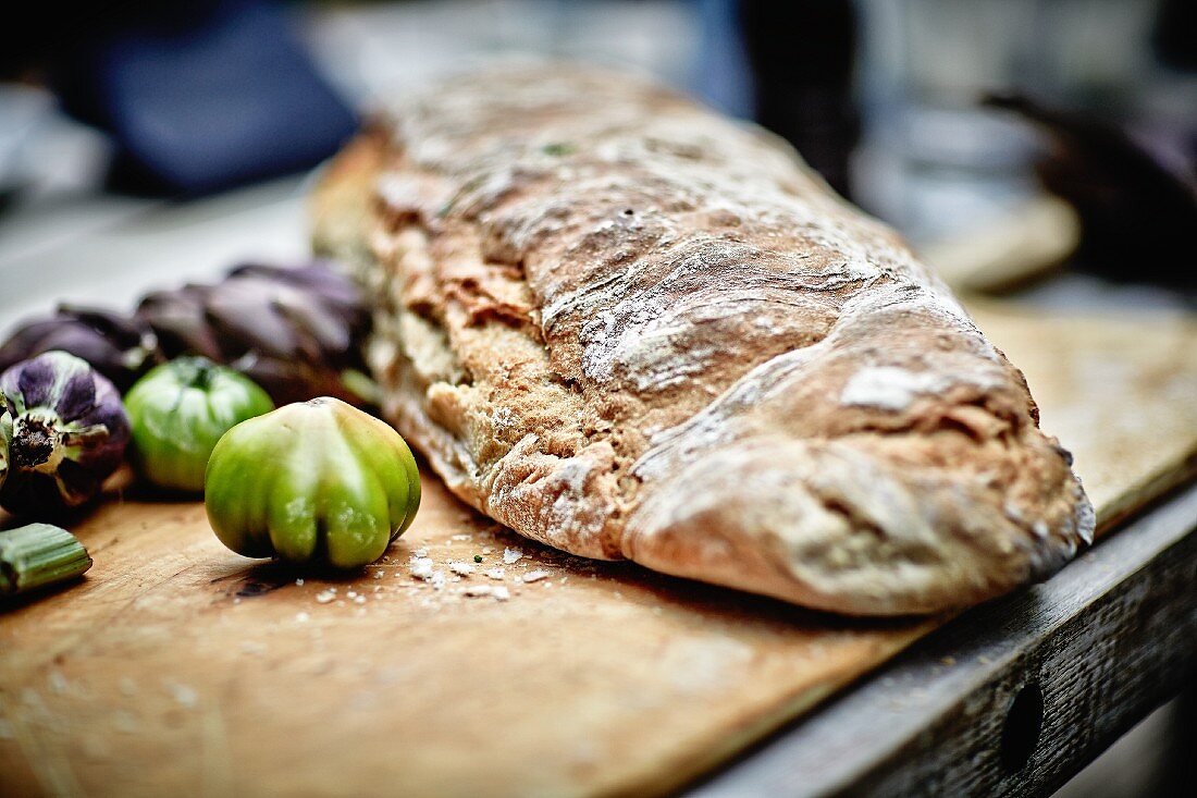 A rustic loaf of bread, artichokes and tomatoes