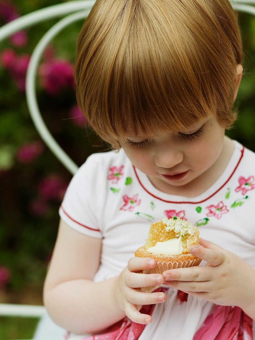 A little girl holding an elderflower cupcake