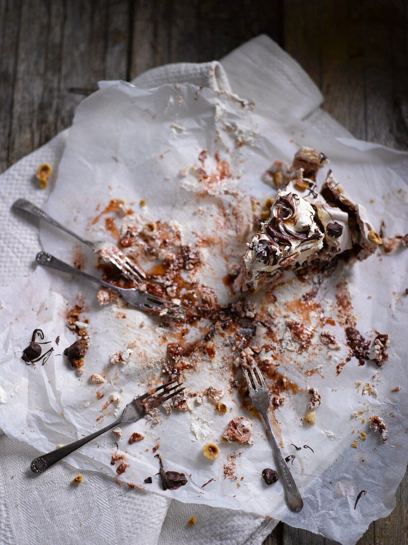 Reste von Pavlova mit Nüssen und Schokolade auf Backpapier