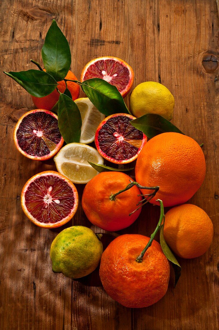 Blutorangen, Mandarinen und Zitronen auf Holzuntergrund (Draufsicht)