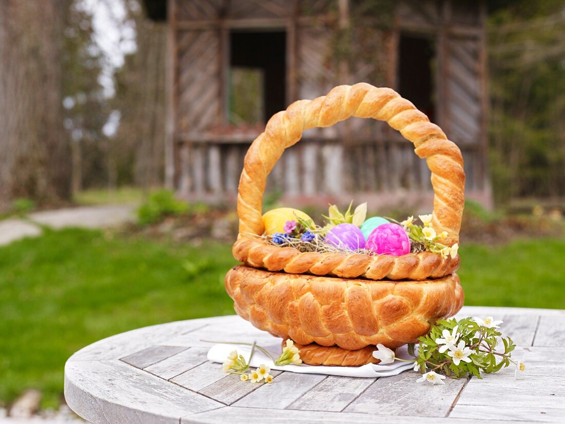 An Easter basket made from bread filled with Easter eggs on a garden table