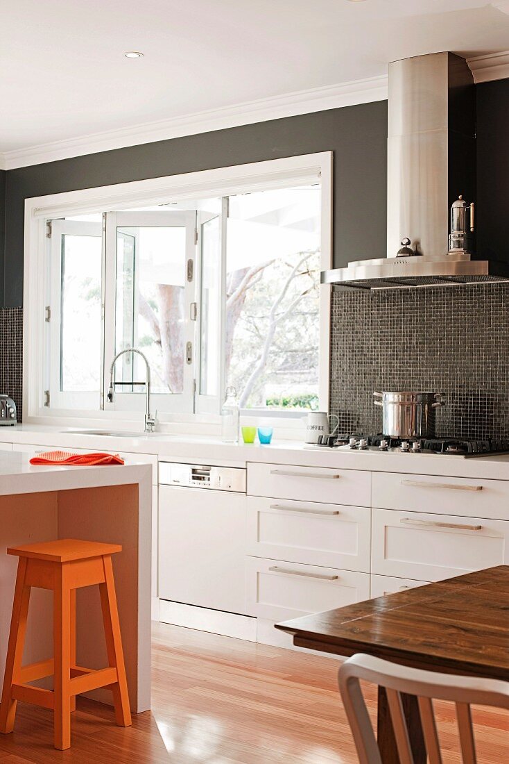Moderne weiße Einbauküche mit dunkel getönter Rückwand