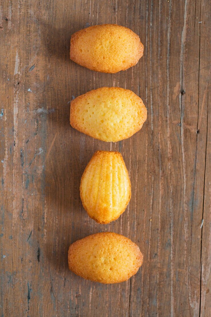 Four madeleines on a wooden surface