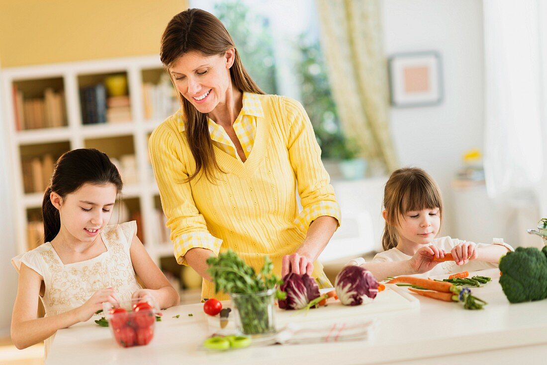 Mutter mit Töchter beim Gemüse schneiden