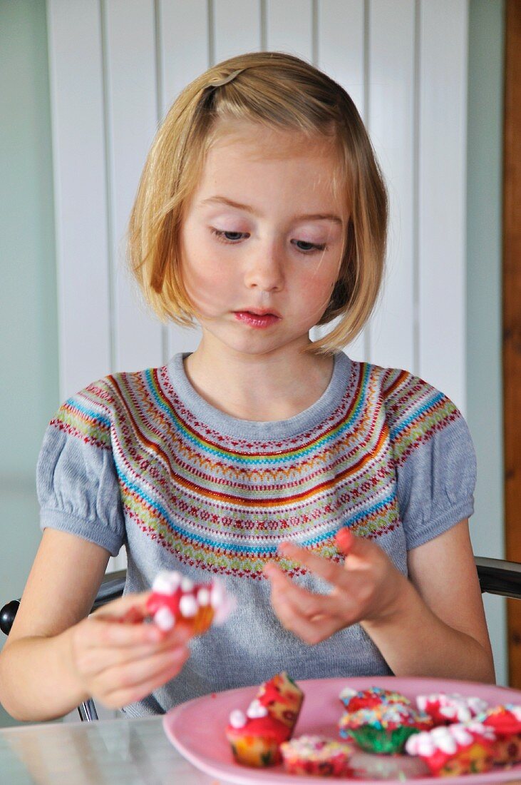 Mädchen verziert Minimuffins in der Küche