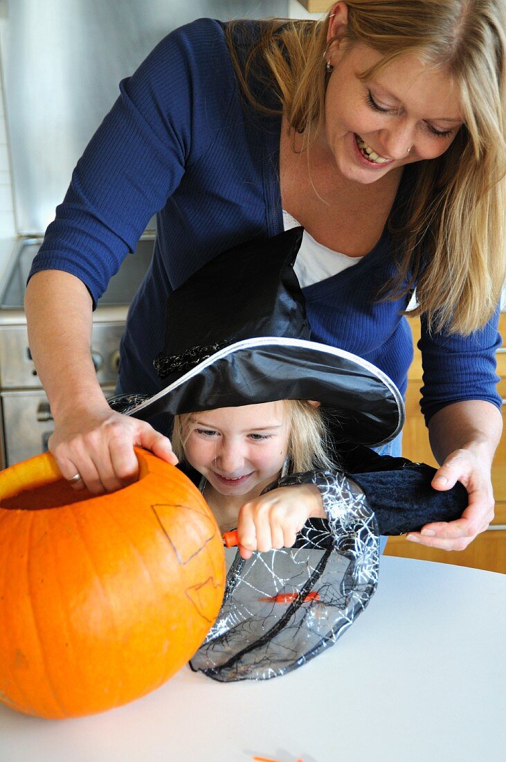 Mutter und Tochter bemalen Halloween-Kürbis