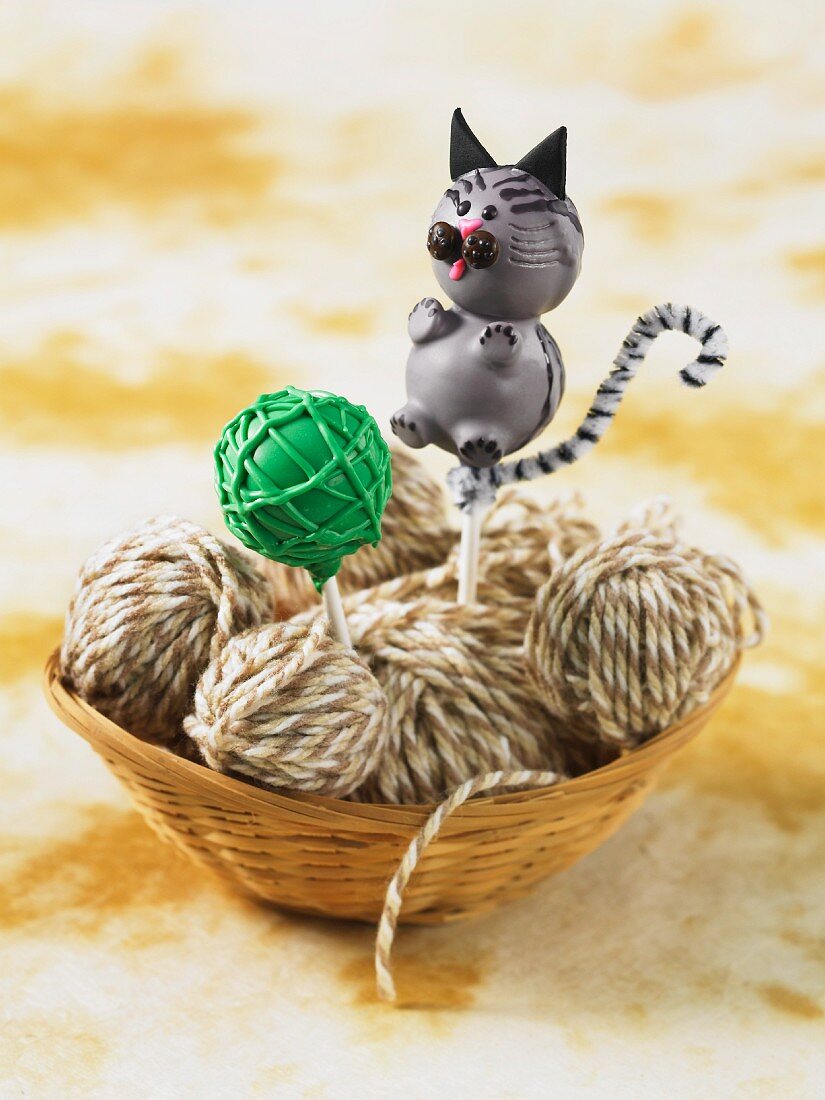 A cat-shaped cake pop in a basket of wool