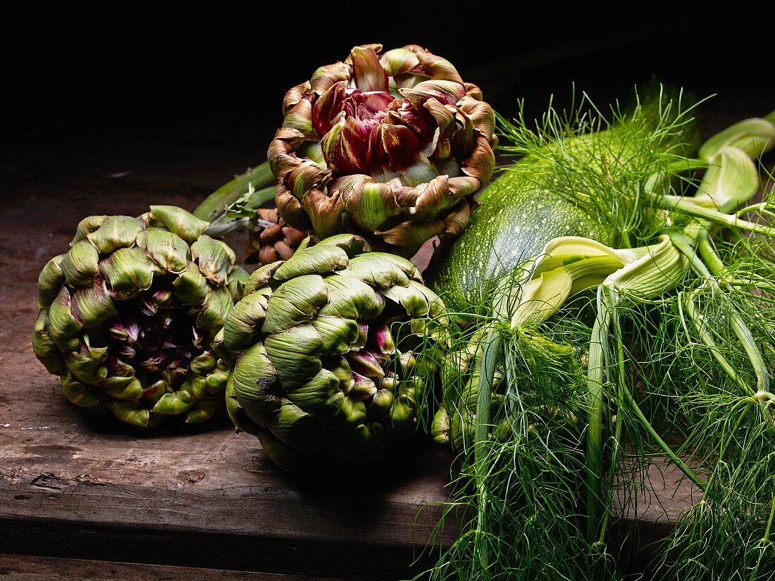 Artichokes, courgettes and dill on a wooden table