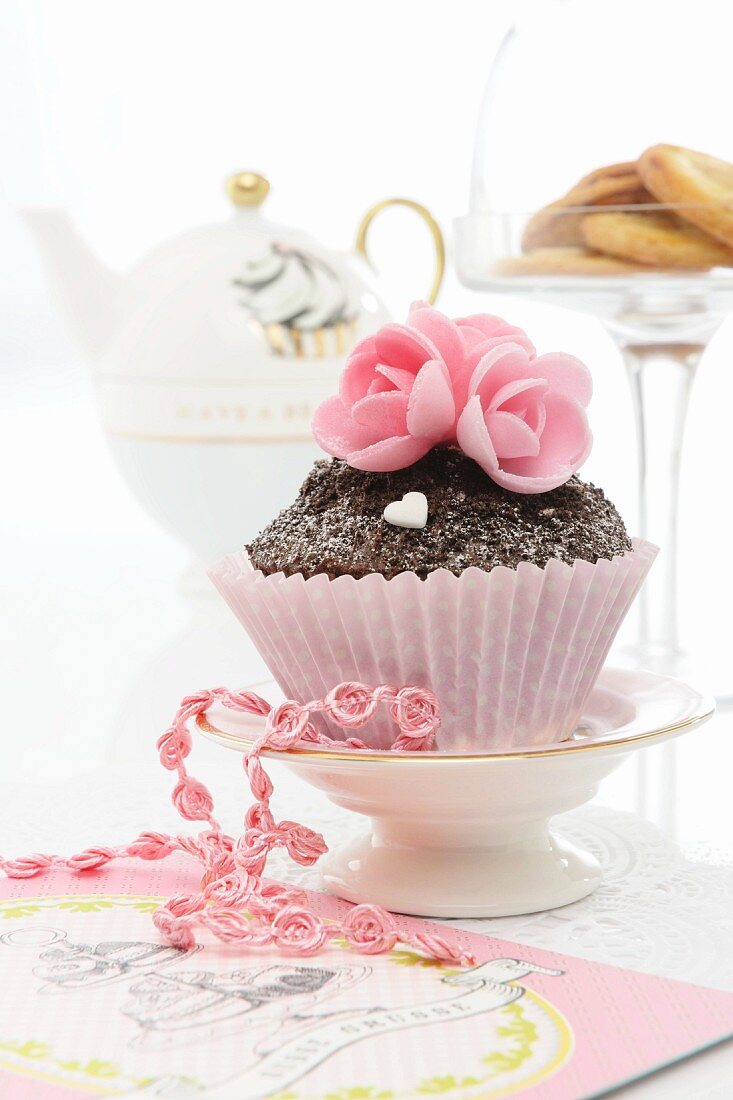 A cupcake decorated with pink sugar flowers for Valentine's Day