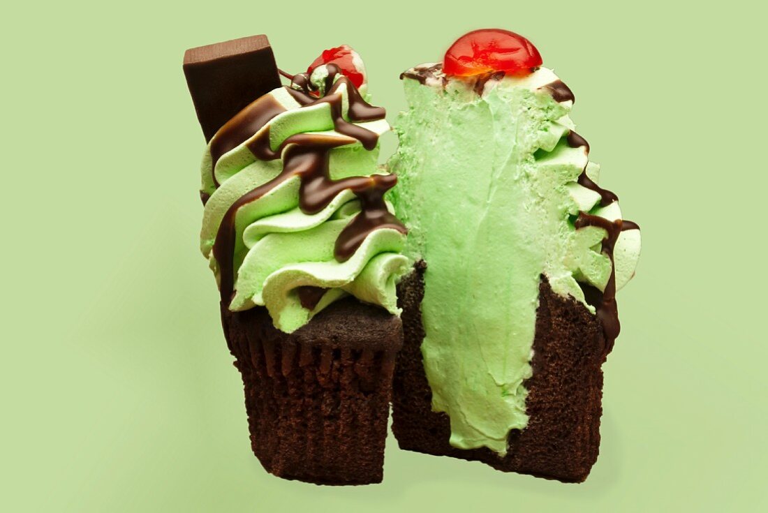 A chocolate cupcake decorated with mint cream, chocolate sauce and a cherry (Christmas)