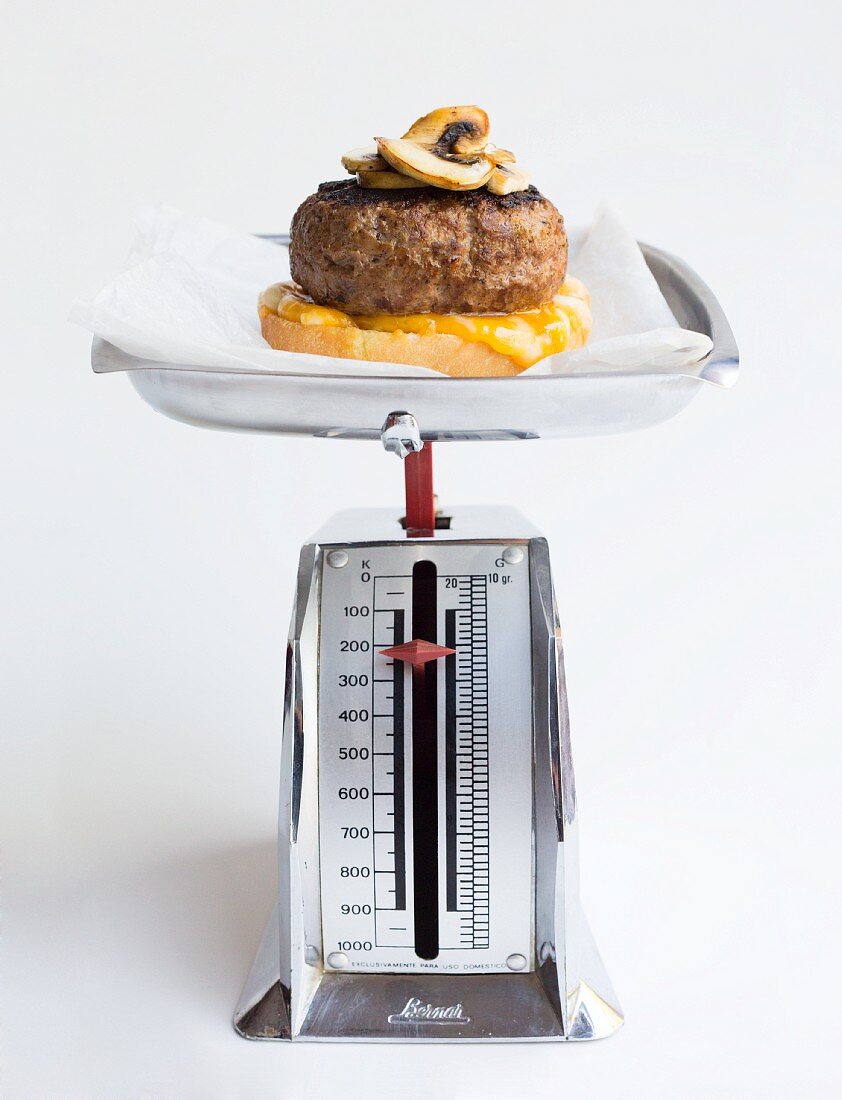 Cheese burger with mushrooms on a pair of mechancial scales