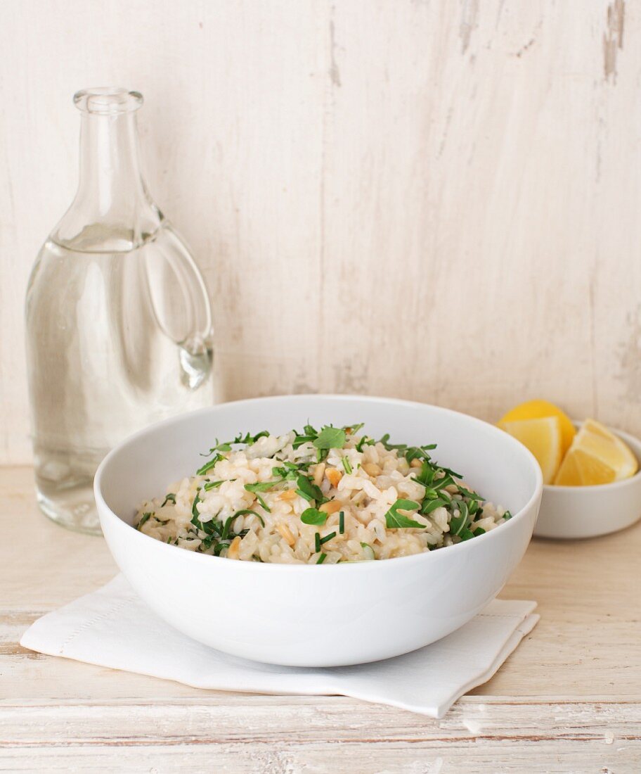 Lemon and rocket risotto with a carafe of water bottle and lemon wedges