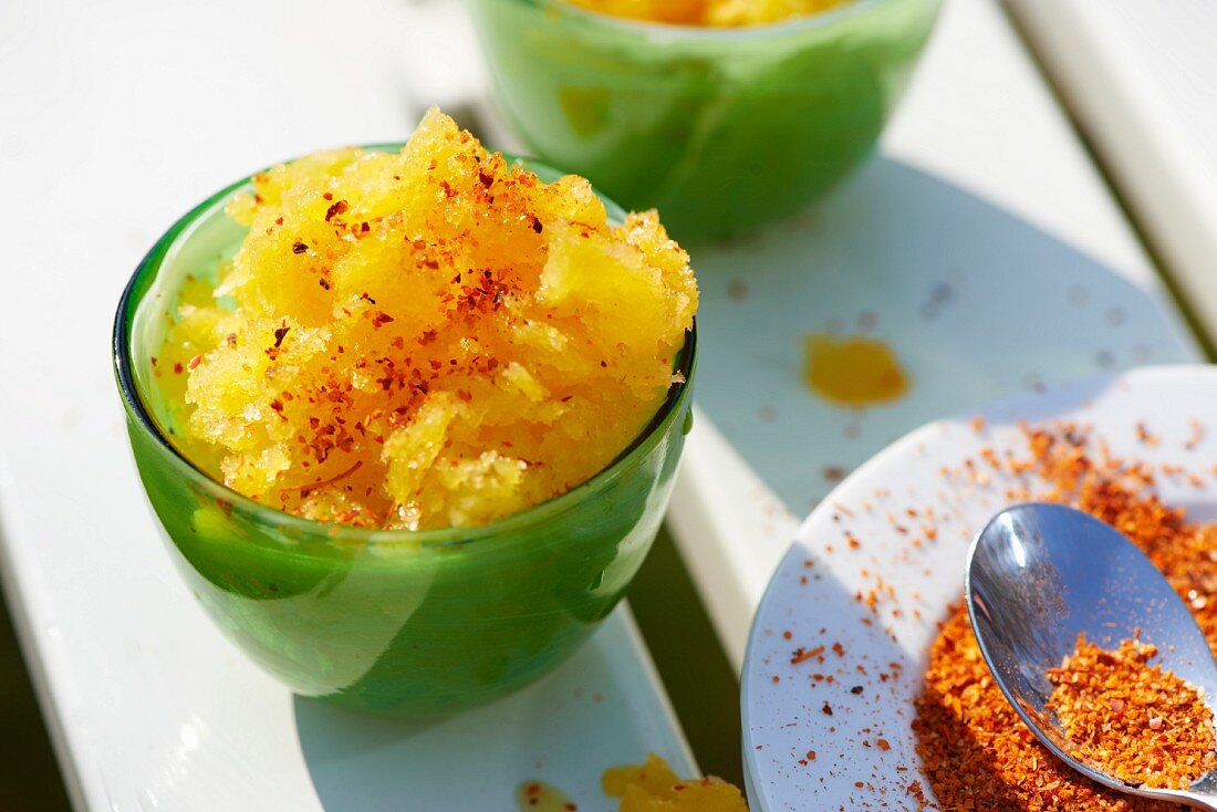 Mango granita dusted with chilli powder in a green glass bowl