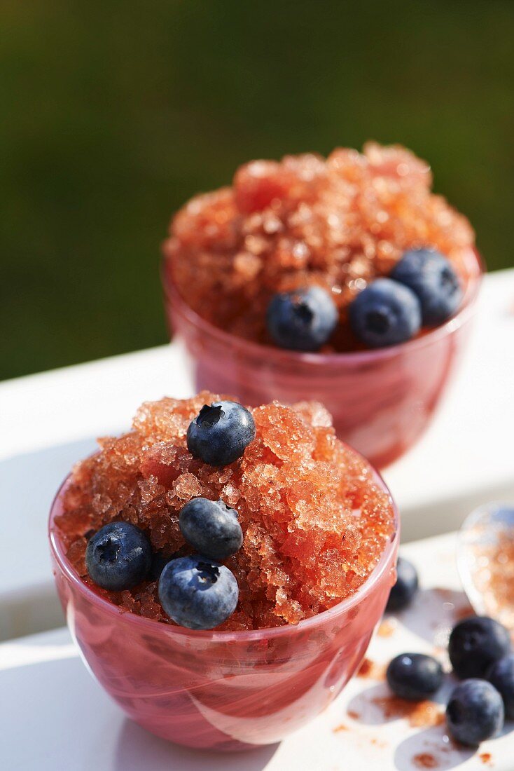 Blaubeer-Granita mit frischen Blaubeeren in rosa Glasschälchen