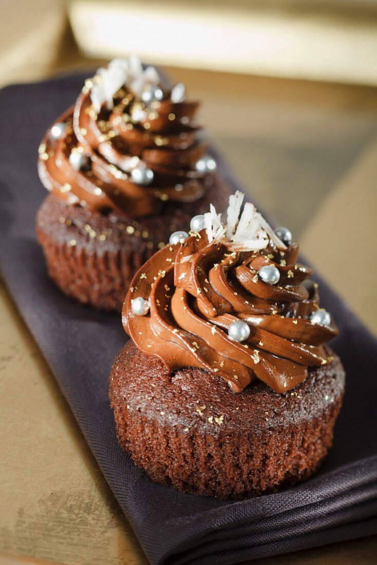 Schokoladen-Cupcakes mit silbernen Zuckerperlen und weissen Schokoraspeln