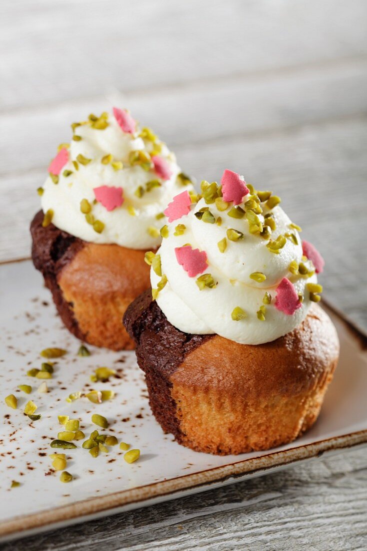 Marble cupcakes topped with white cream, pistachios and pink sugar Christmas trees