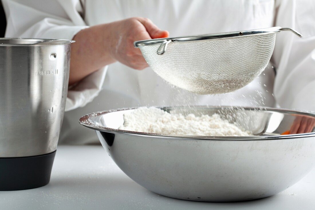 Flour being sifted into a large mixing bowl