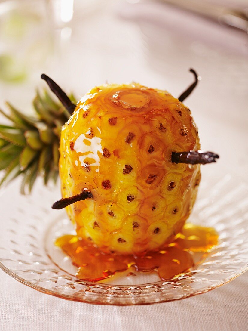 A caramelised pineapple with cinnamon sticks