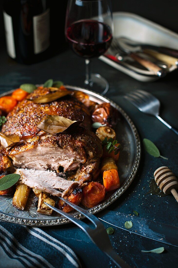 Sliced roasted pork with a side of vegetables and red wine