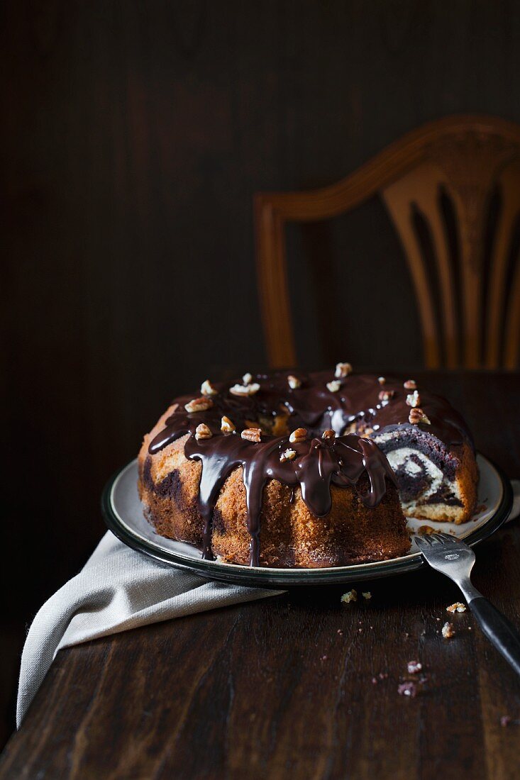 Marble cake with chocolate glaze and pecan nuts, sliced