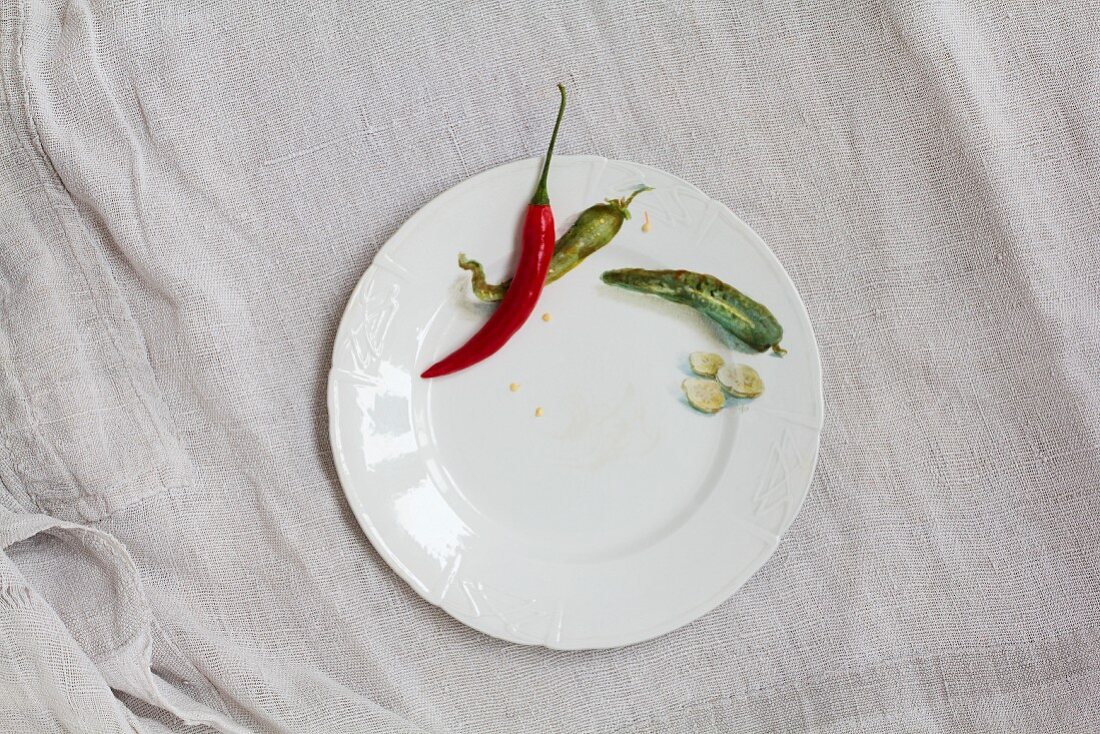 Chilli peppers and slices of cucumber on a white porcelain plate