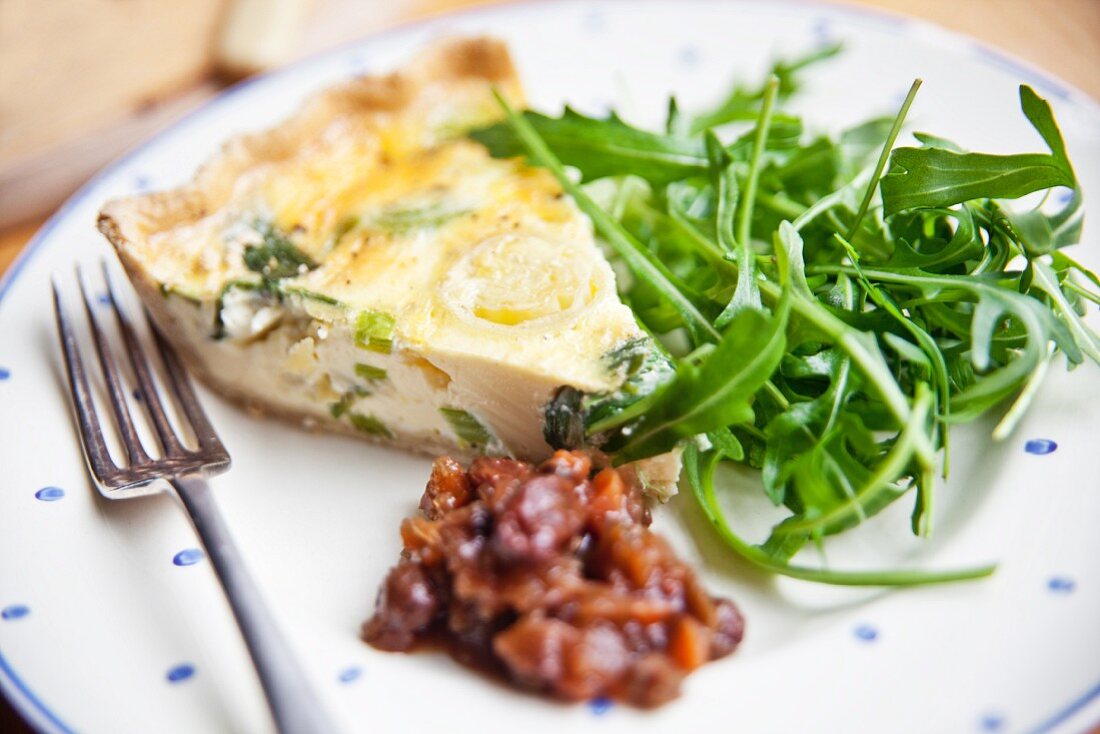 A slice of cheddar and leek quiche with rocket and apple chutney