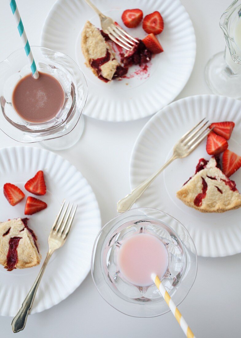 Three slices of strawberry pie with fresh strawberries and milk shakes