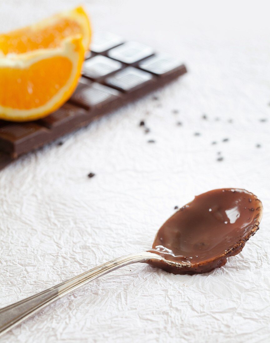 Löffel mit Schoko-Orangen-Pudding, dahinter Zutaten