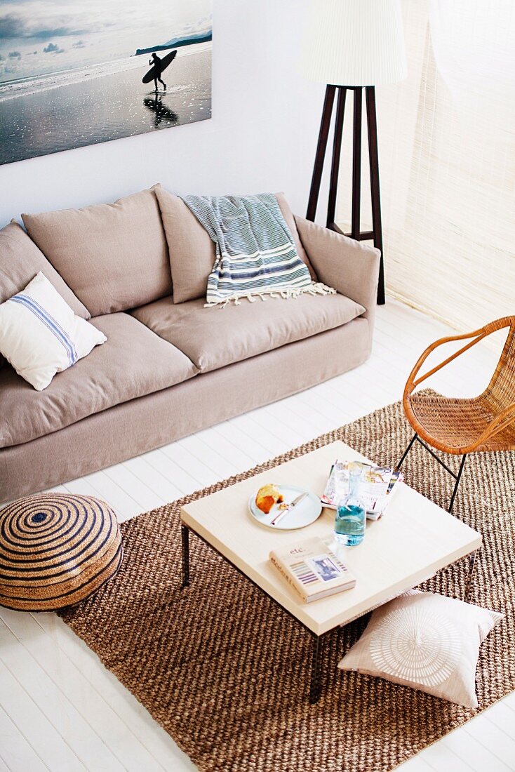 View down onto coffee table and sisal rug next to sofa against wall below large photograph