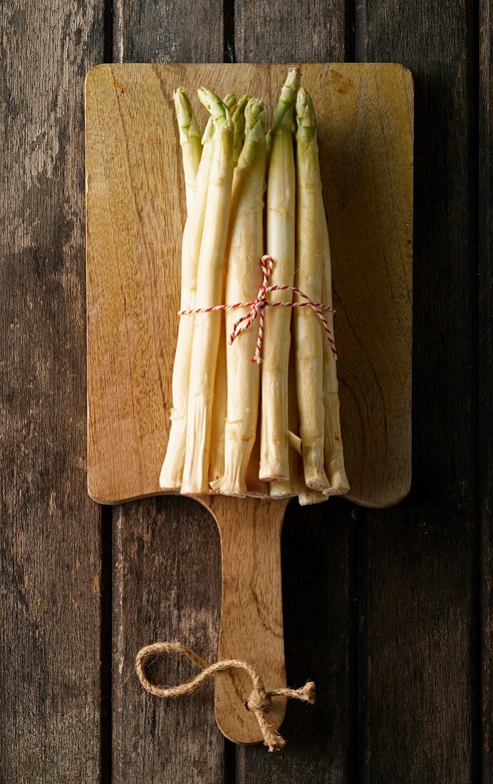 A bunch of fresh white asparagus on a chopping board