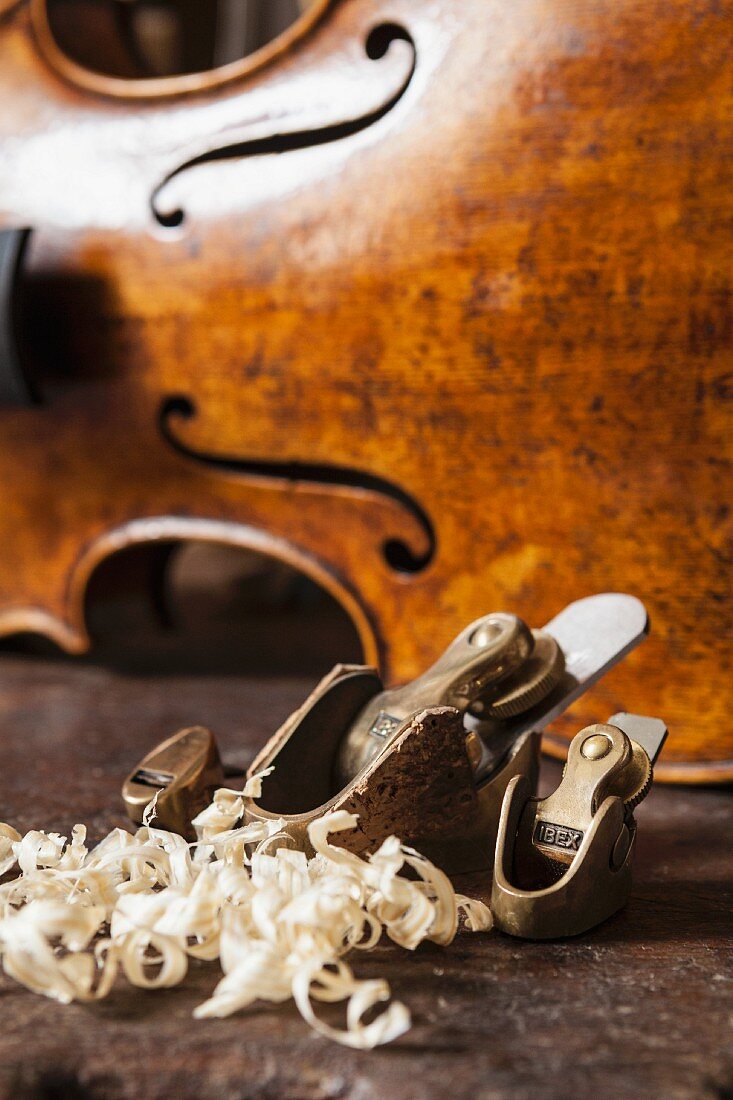Wood shavings and violin-maker's plane in front of violin body