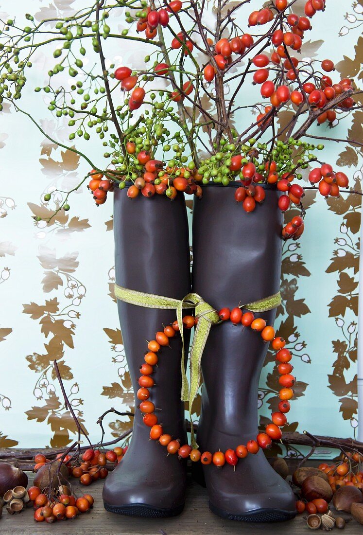 Wreath of rose hips tied to wellington boots filled with branches of rose hips