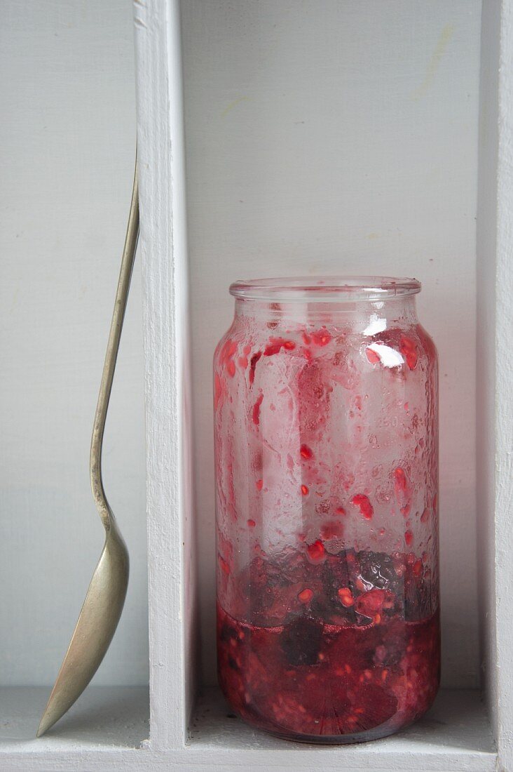 Himbeer-Cranberry-Marmelade im Glas, halb aufgegessen