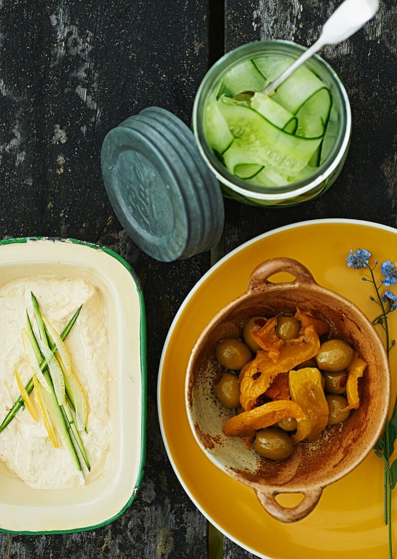 Picknicktisch mit Paprika-Oliven-Gemüse, Gurkensalat und Gemüsecreme