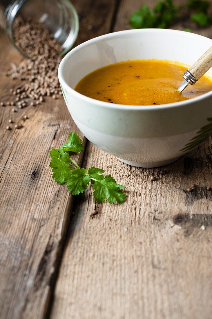 Karotten-Koriander-Suppe auf rustikalem Holzuntergrund