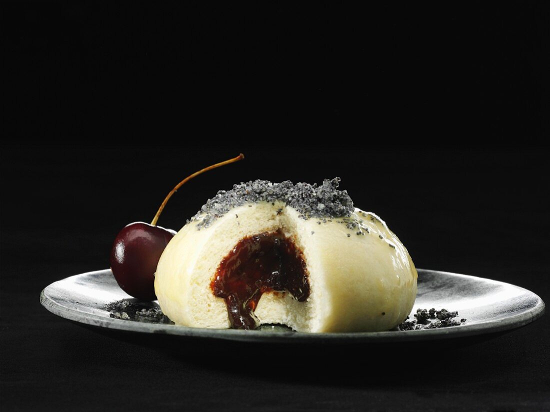 A Germknödel (yeast dumpling filled with jam) with poppyseeds and cherry sauce