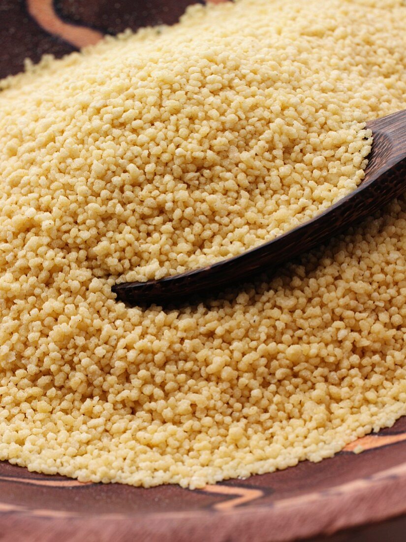 A wooden spoon in a pile of cooked couscous