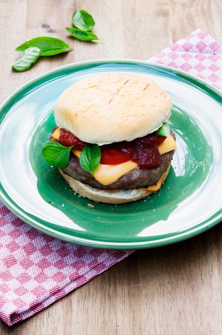 Grilled cheeseburger with tomatoes and basil on a green plate