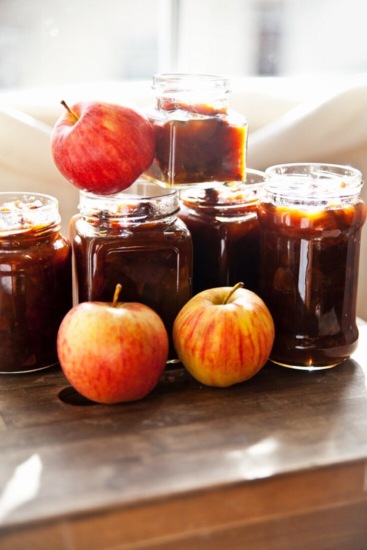 Jars of homemade apple chutney and fresh apples