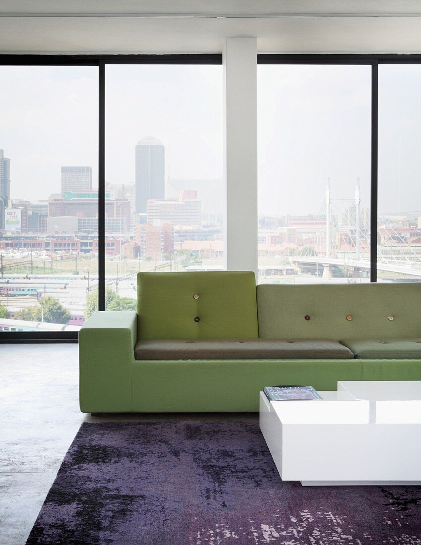 Polder sofa in shades of green and white coffee table in loft apartment with view of Johannesburg, South Africa