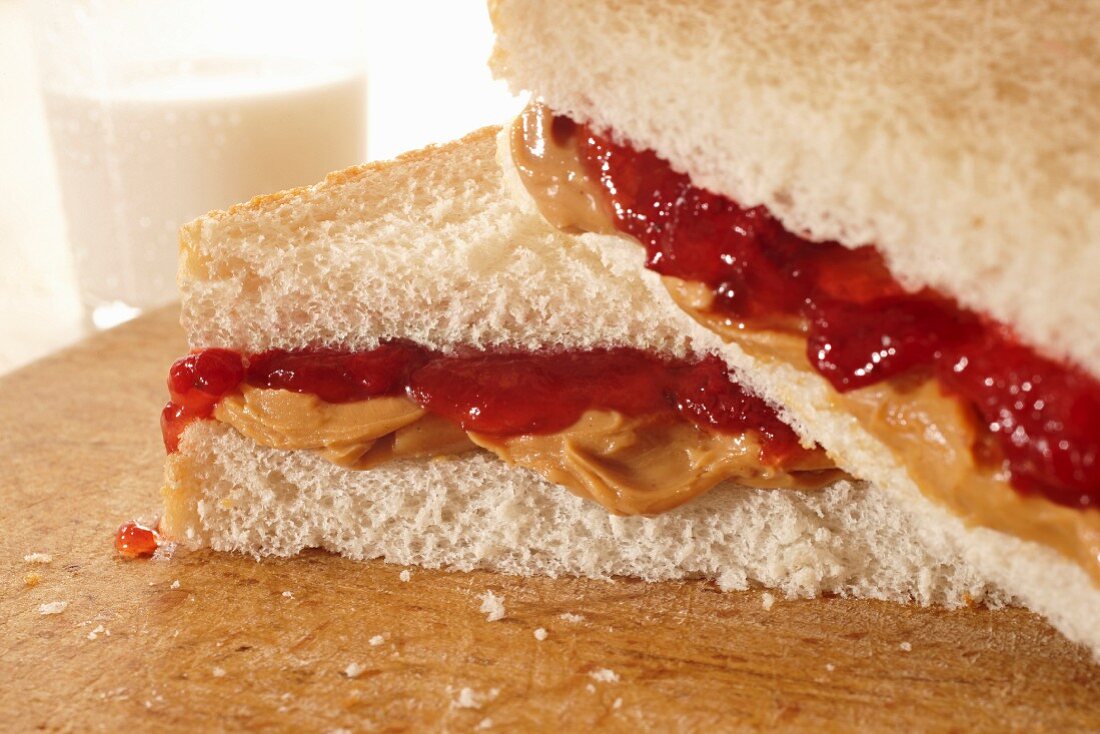 A peanut butter and jam sandwich with a glass of milk