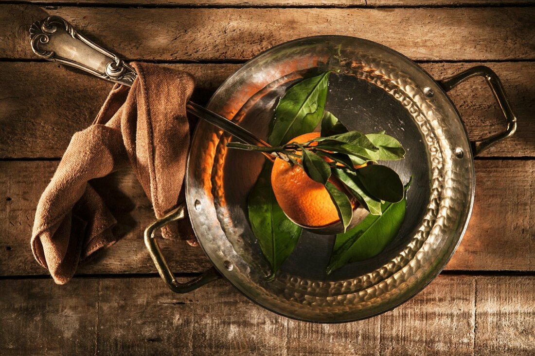 A freshly picked orange in a copper saucepan