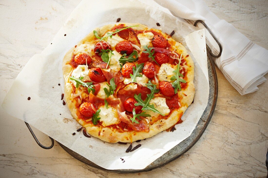 Pizza mit Prosciutto, Mozzarella, Tomaten und Rucola