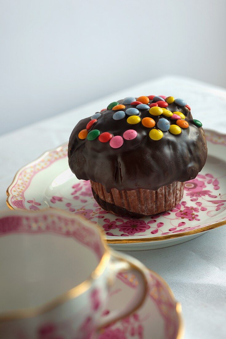 A cupcake with chocolate glaze and chocolate beans