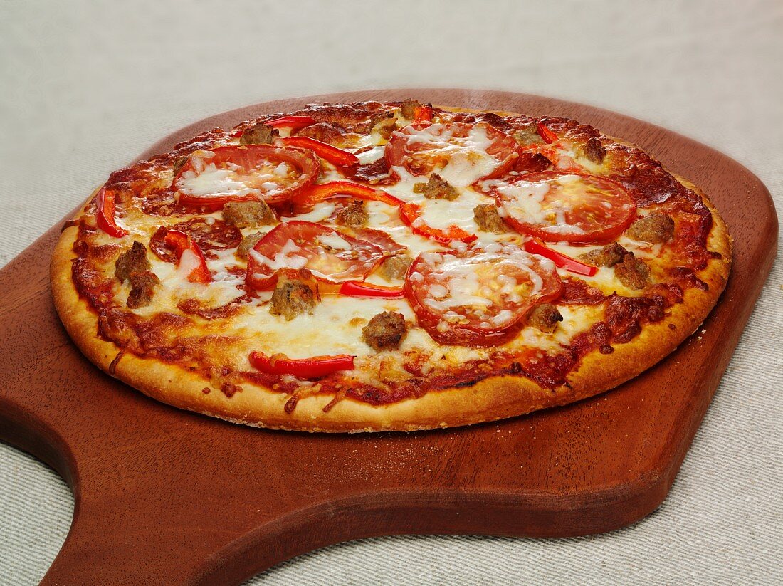 Pizza mit Peperoniwurst, Paprika und Mozzarella auf Schneidebrett