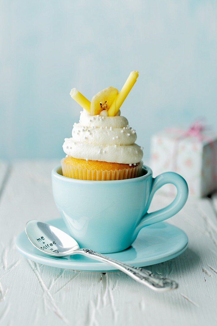 Bananen-Honig-Cupcake in blauer Tasse mit Teelöffel und Geschenk