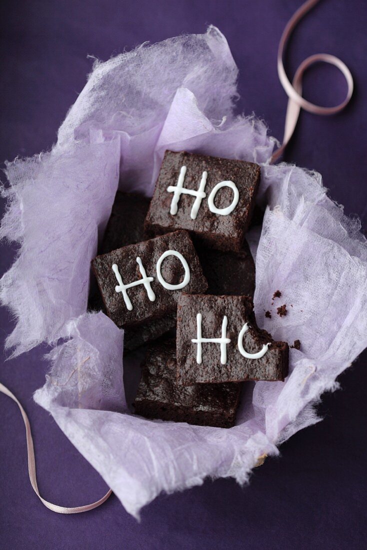 Brownies decorated with the words 'Ho, ho, ho' on a purple surface