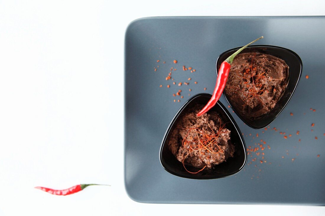 Zwei Portionen Schokoladen-Chili- Mousse mit Chilischoten und Chilifäden